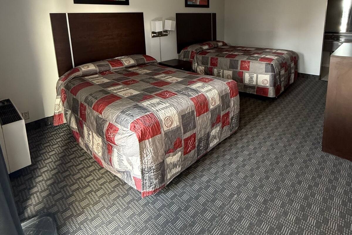 Habitación de hotel con dos camas, un escritorio, una silla, una mesita y un microondas.