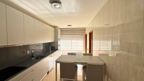 Een moderne keuken met een eethoek, met een ingebouwde oven, een spoelbak en een eettafel met stoelen.