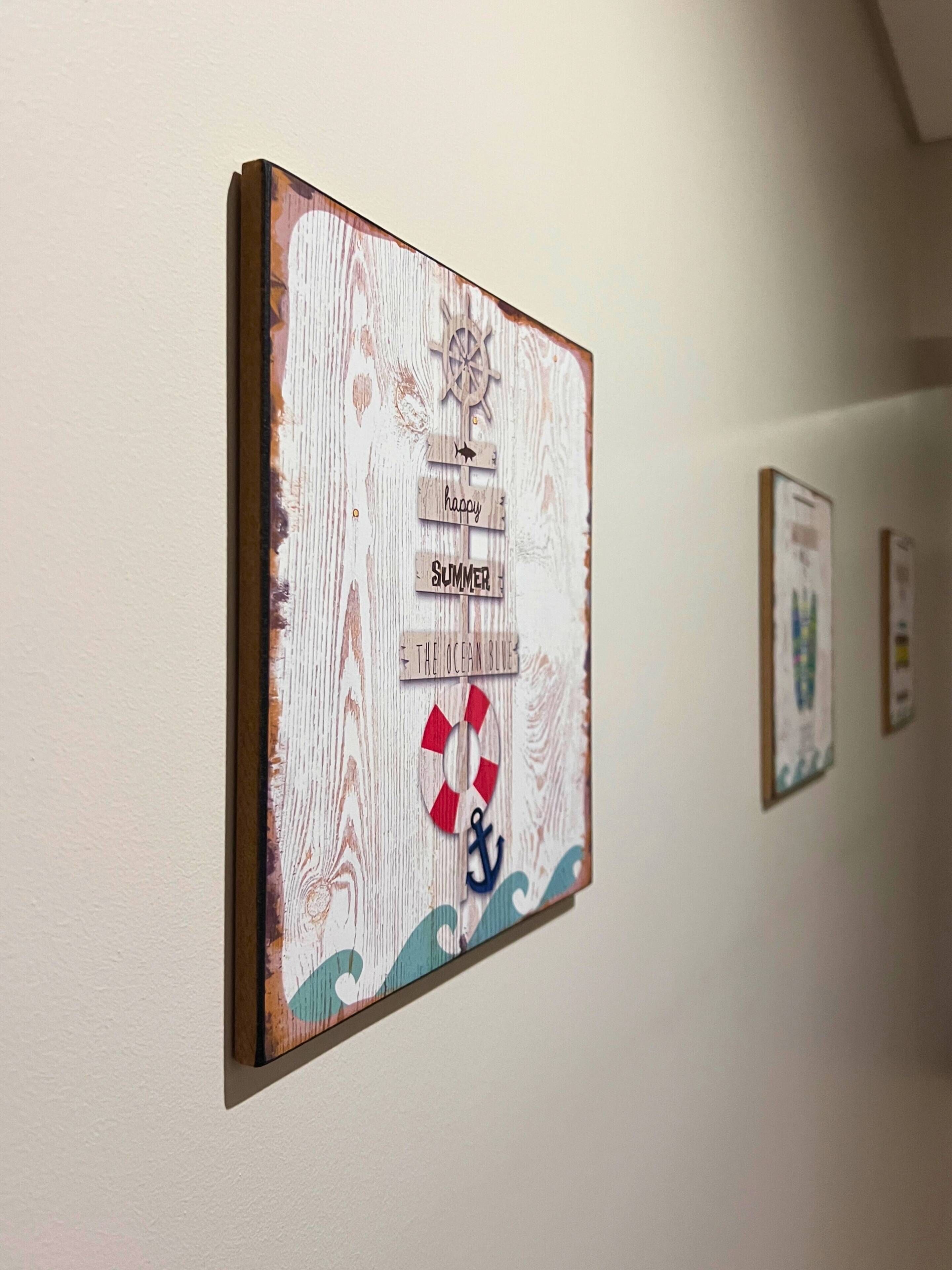 A wall with a nautical-themed artwork featuring a ship's wheel, a lifebuoy, and the words 'happy summer the ocean blue.'
