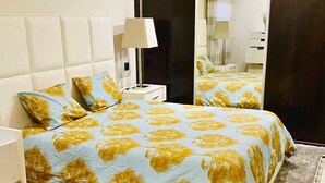 Een slaapkamer met een bed, een nachtkastje, een lamp, een spiegel en een vloerkleed.