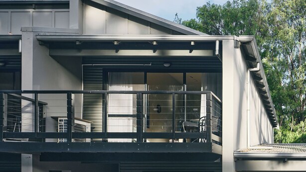 Ein modernes, zweistöckiges Gebäude mit Balkon, großen Fenstern und einer Garage.