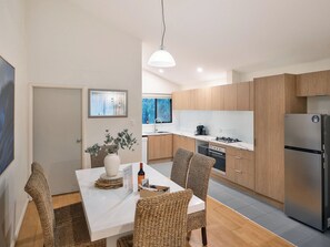 Une cuisine moderne avec des meubles en bois, un plan de travail blanc et un réfrigérateur en acier inoxydable.