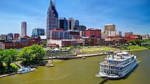 A river with a large white boat docked on the right, surrounded by buildings including a distinctive tall skyscraper.