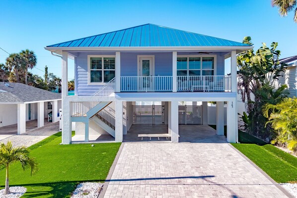 A two-story house with a blue roof, a covered porch, and a staircase leading to the second floor.