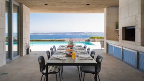Spisestue med havudsigt, en pool og moderne arkitektur.