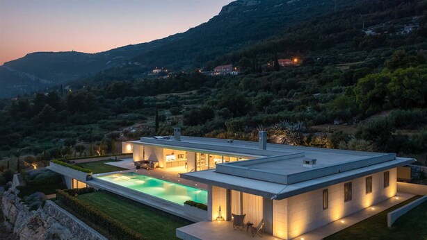 Et moderne hus med swimmingpool, store vinduer og udsigt til de omkringliggende bakker.