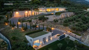 En moderne villa med stor terrasse, swimmingpool og udsigt over det omkringliggende landskab.