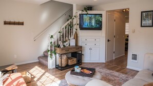 A living room with a staircase, a television mounted above a cabinet, and a sofa.