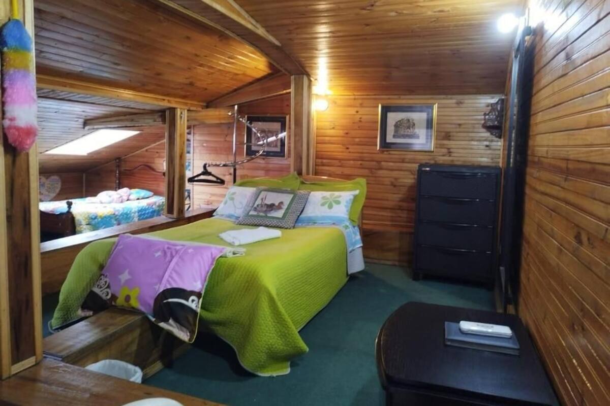 A cozy wooden cabin bedroom with two beds, a dresser, and a small table.