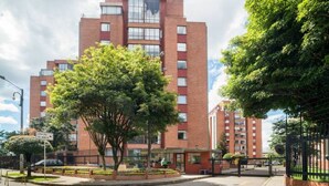 Un edifici de diverses plantes amb un pati central, envoltat d'arbres i una entrada tancada per una reixa.