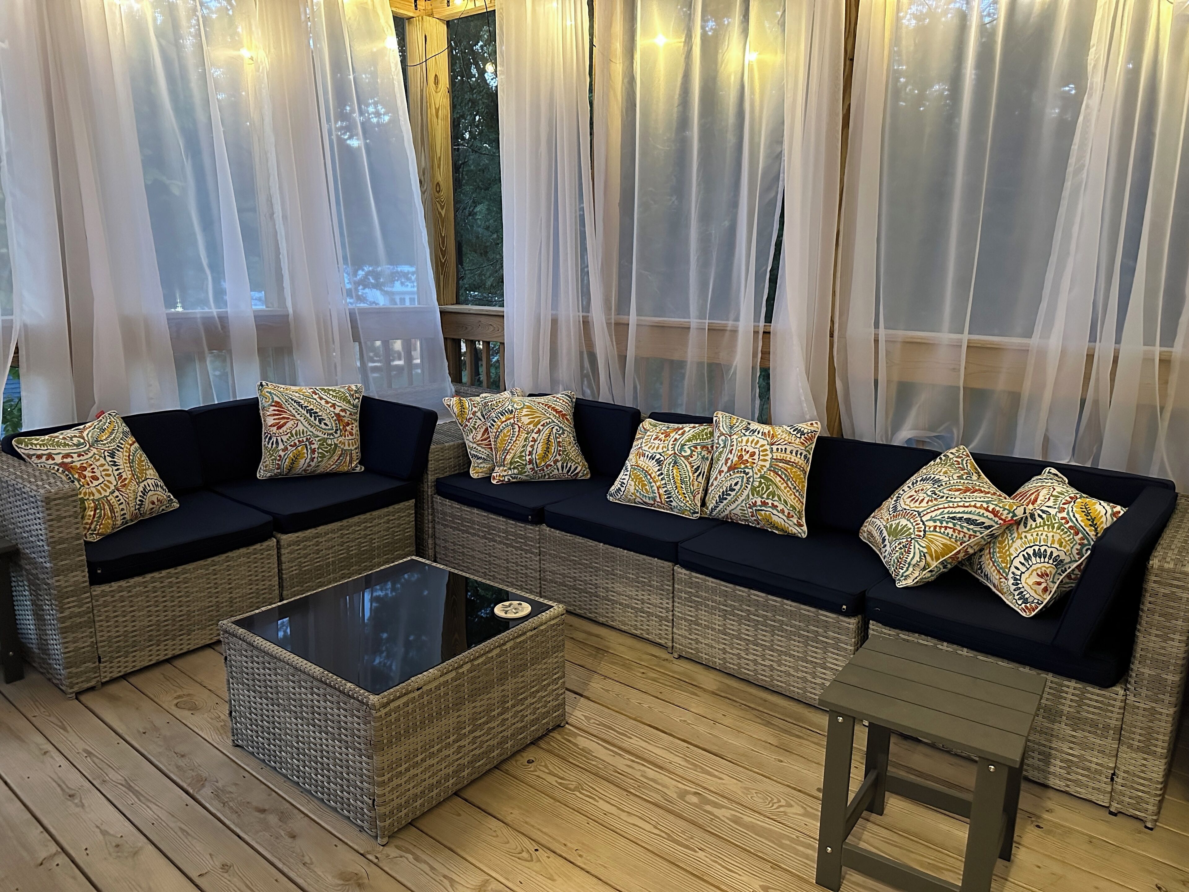 A cozy seating area with a wicker sofa set, patterned cushions, and a glass-top coffee table.