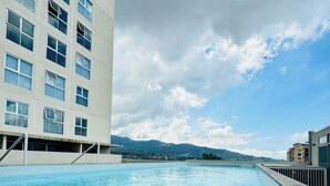 Una piscina con vistas a un edificio moderno y montañas distantes.