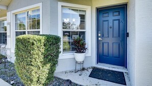 Une maison avec une porte bleue, des fenêtres blanches et une petite plante en pot sur le porche.