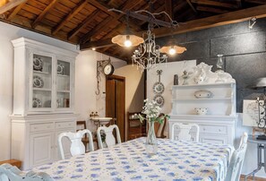 Un coin repas avec une table dressée pour quatre personnes, des meubles blancs aux portes vitrées, un lustre et une horloge au mur.