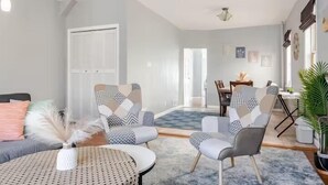 A modern living room with a sofa, two armchairs, a coffee table, and a dining area with a table and chairs. - Free parking, Safe Area -close to NYC and Newark Airport,  2-bedroom apartment. (Bayonne)