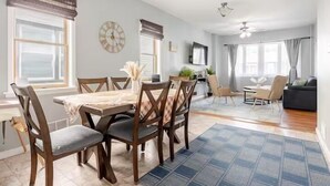 A spacious living room with a dining area, large windows, and a modern ceiling fan. - Free parking, Safe Area -close to NYC and Newark Airport,  2-bedroom apartment. (Bayonne)