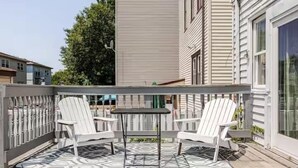 A deck with two white Adirondack chairs and a small table, surrounded by a grey railing. - Free parking, Safe Area -close to NYC and Newark Airport,  2-bedroom apartment. (Bayonne)