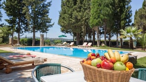 A poolside area with lounge chairs and a fruit basket. - Attractive Villa, A/C, Large Private Pool & Idyllic Setting in the Sought-After Area of Gastouri! (Kerkira)