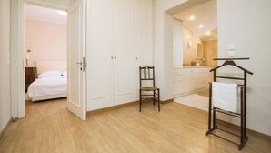 A bedroom with a bed, a chair, a wardrobe, and a bathroom with a mirror and towel rack. - Attractive Villa, A/C, Large Private Pool & Idyllic Setting in the Sought-After Area of Gastouri! (Kerkira)