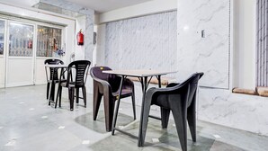 A dining area with a marble wall, a fire extinguisher, and a window with blinds. - KINGS COURT HOTEL  (New Delhi)