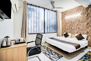 A hotel room with a bed, desk, chair, and a view of the city through large windows. - KINGS COURT HOTEL  (New Delhi)