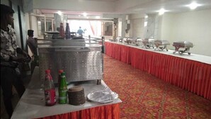 A banquet hall with a long table covered in a red tablecloth, lined with silver buffet trolleys. - KINGS COURT HOTEL  (New Delhi)