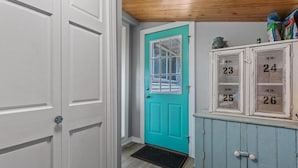 A teal door with a window, a white door, and a cabinet with numbered compartments. - Tradewinds Cabin on Big Cormorant (Audubon)