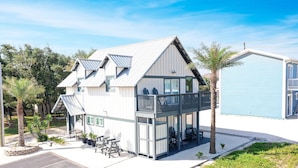 A two-story building with a balcony, outdoor seating, and a small garden area.