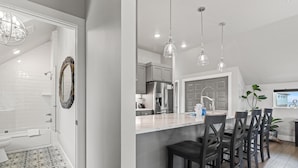 A modern kitchen with a central island, stainless steel appliances, and pendant lighting.