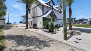 A two-story building with a flat roof and a gravel driveway. - Sugar Sand Cottage B (Port St. Joe)