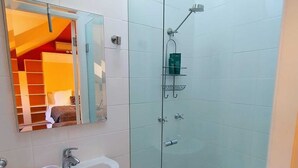 Ein Badezimmer mit Duschkabine aus Glas, Waschbecken mit Seifenschale und Spiegel über dem Waschbecken.