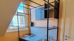 Eine kleine Küchenzeile mit Spüle, Schränken und einem Fenster.