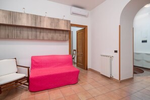 A room with a wooden ceiling, a white radiator, a wooden door, and a pink sofa.