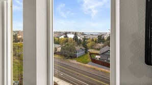A view from a window overlooking a street with houses, a road, and a large white dome structure in the distance. - Top floor corner condo with UNREAL views of Commencement Bay + DT Tacoma skyline (Tacoma)