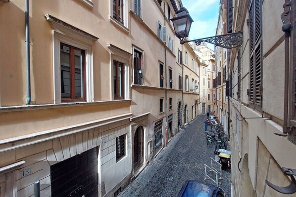 A narrow street with buildings on either side, a cobblestone road, and a few parked bicycles.