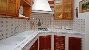 Une cuisine équipée d’un évier, d’une cuisinière, de meubles de rangement en bois et d’un crédence décorée.
