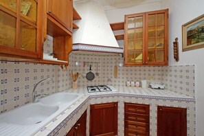 A kitchen with a sink, stove, wooden cabinets, and patterned backsplash.
