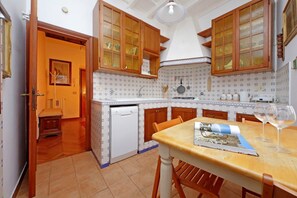 Une cuisine avec des meubles de rangement en bois, un lave-vaisselle blanc et une table à manger avec des chaises.