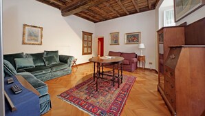 Un salon avec un plafond en bois, un canapé vert, une table ronde et un tapis à motifs.