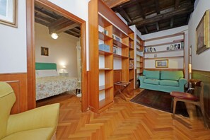 Ein Zimmer mit einem Bett, einem grünen Sofa, Holzregalen und einem Holzstuhl.