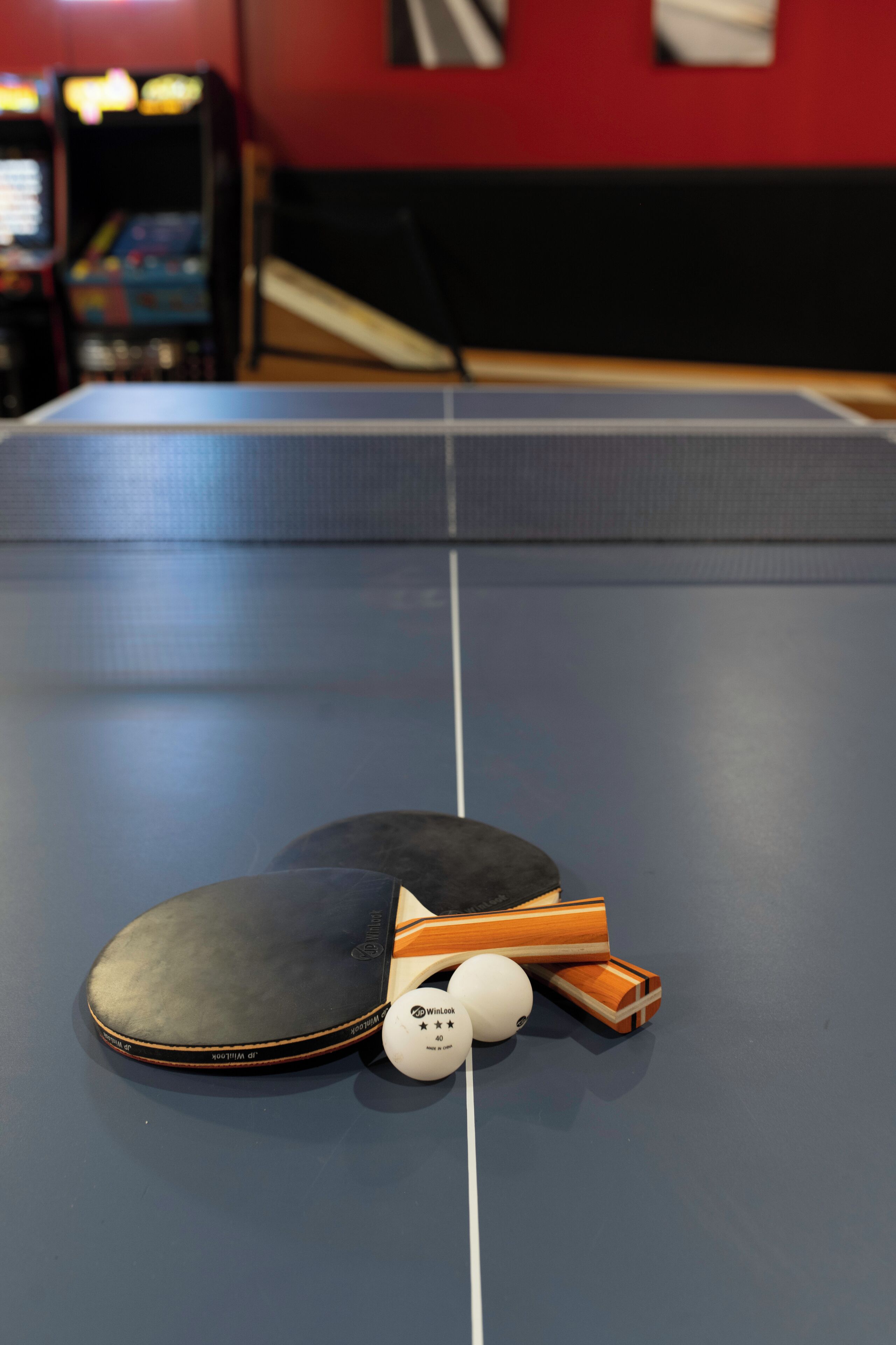 A ping pong table with a paddle, balls, and a table tennis ball.