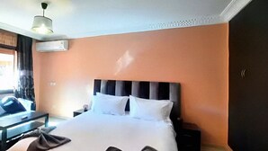 Una habitación de hotel con una cama grande, una mesita de noche, una silla y un armario.