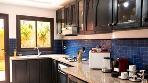 Una cocina moderna con armarios oscuros, encimera de granito y ventana con vistas a zonas verdes.