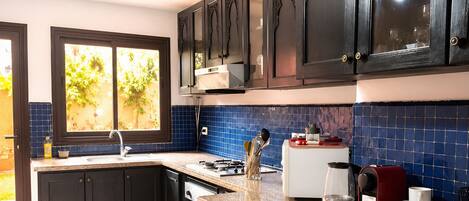 A modern kitchen with dark cabinetry, a granite countertop, and a window with a view of greenery.