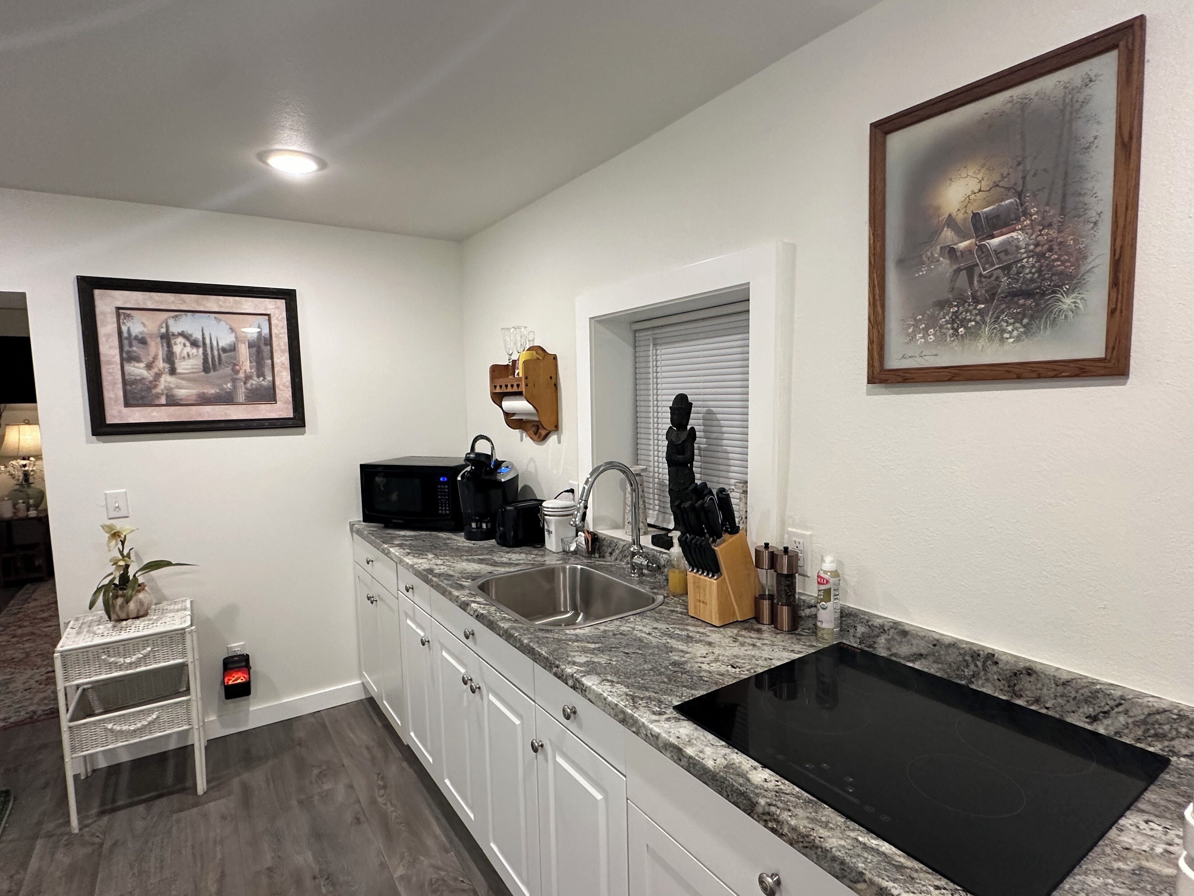 A modern kitchen with white cabinets, a black stove, and a granite countertop.