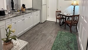 Una cucina compatta con mobili bianchi, un piano di lavoro in granito, un frigorifero e un'area pranzo con tavolo e sedie.