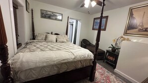 Una camera da letto con un letto a baldacchino, una ventola a soffitto, un tappeto floreale e quadri appesi alle pareti.