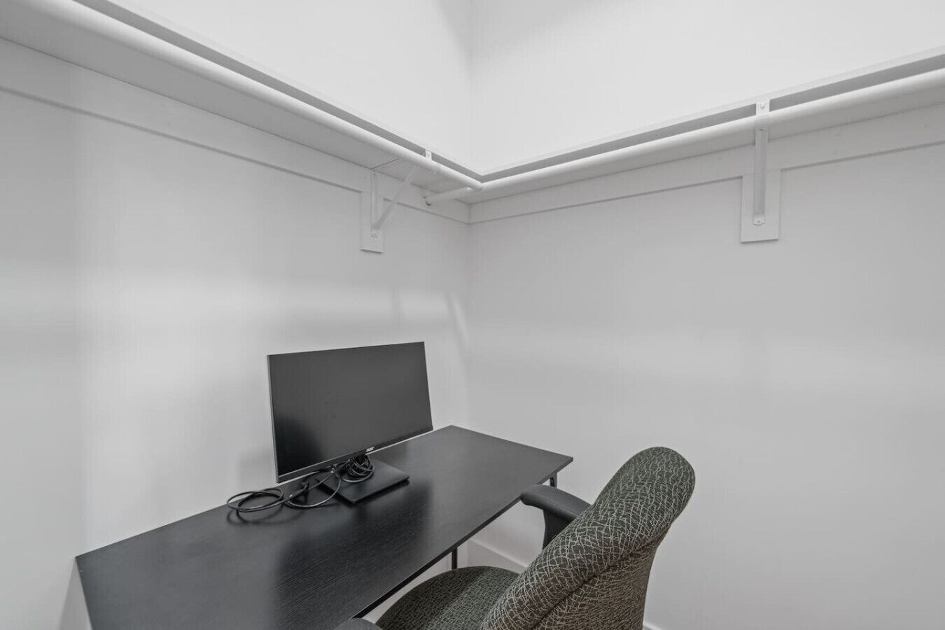 A small, modern room with a desk, chair, and a flat-screen TV.