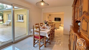 A dining area with a table set for four, a wooden cabinet, and a television in the background.