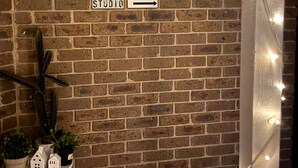 Un mur de briques avec un panneau indicateur pointant vers la droite, sur lequel est inscrit le mot « STUDIO ».